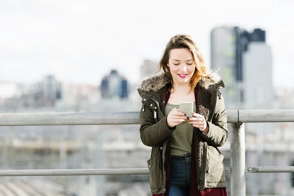 Chica feliz mensajes de texto en un teléfono inteligente . — Foto de Stock