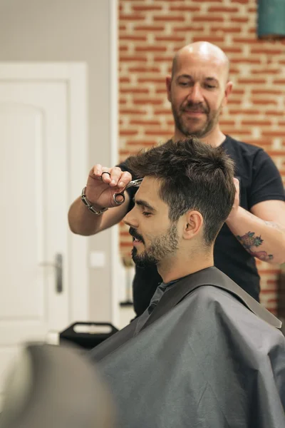 Peluquero haciendo corte de pelo de hombres a un hombre atractivo . — Foto de Stock
