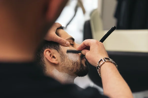 Bärtiger Mann bekommt vom Friseur eine Bartfrisur mit Rasiermesser — Stockfoto