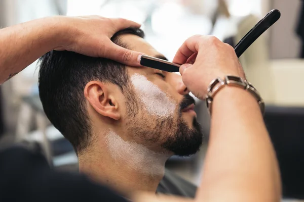 Homem barbudo ficando barba corte de cabelo com uma navalha pelo barbeiro — Fotografia de Stock