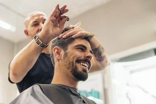 Coiffeur faire la coupe de cheveux des hommes à un homme attrayant . — Photo