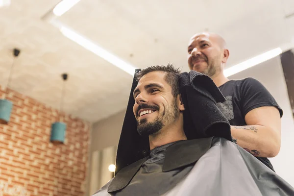 Hairstylist making men's haircut to an attractive man. — Stock Photo, Image