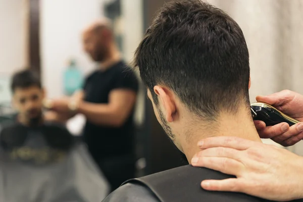 Coiffeur faire la coupe de cheveux des hommes à un homme attrayant . — Photo