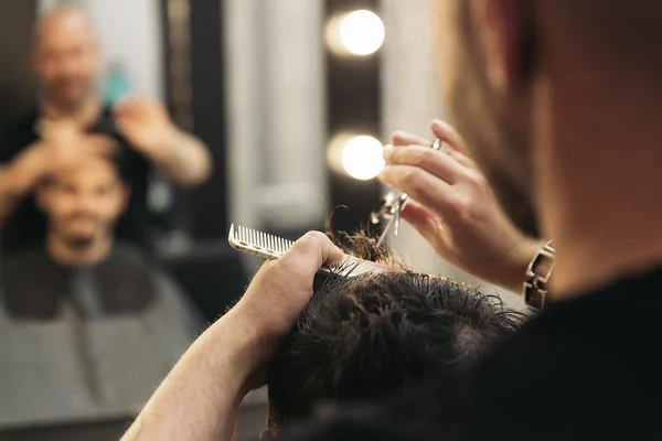 Haarstylist mannen kapsel aanbrengt een aantrekkelijke man. — Stockfoto