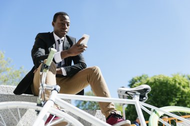 Cep telefonunu kullanırken gülümseyen yakışıklı Afrika adam.