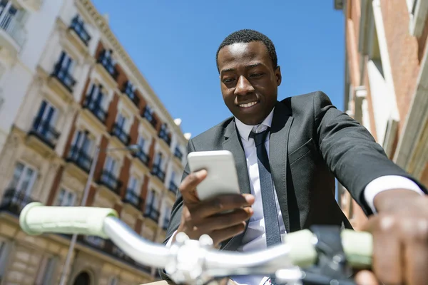 Schöner afrikanischer Mann lächelt, wenn er sein Handy benutzt. — Stockfoto