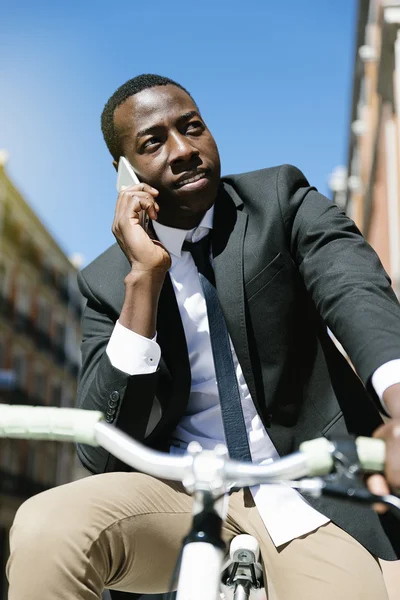 Afrikai férfi mozgatható telefon és kerékpár. — Stock Fotó