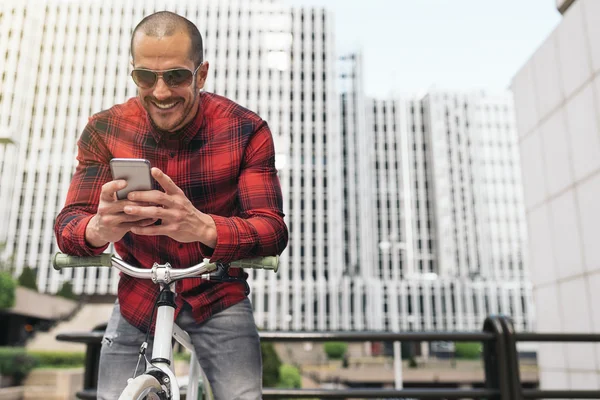 Молодий чоловік з мобільним телефоном і велосипедом з фіксованою передачею . — стокове фото