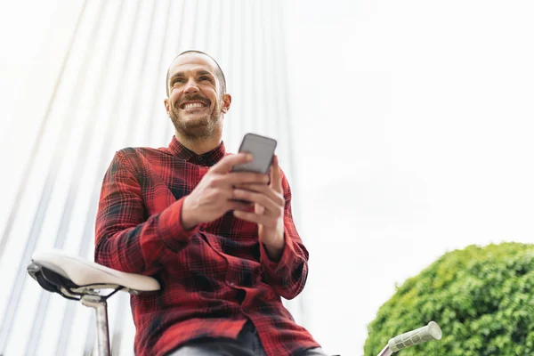 Genç adam cep telefonu ve sabit vites bisiklet. — Stok fotoğraf