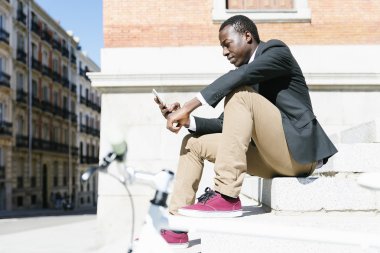 Cep telefonunu kullanırken gülümseyen yakışıklı Afrika adam.