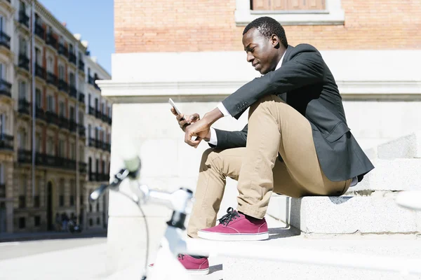 Cep telefonunu kullanırken gülümseyen yakışıklı Afrika adam.