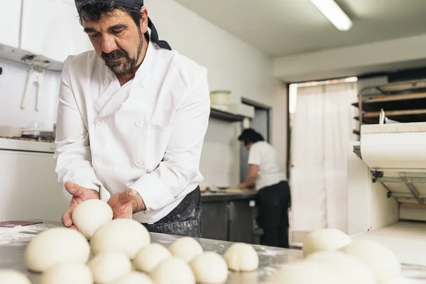 Panadero amasando masa en una panadería. —  Fotos de Stock