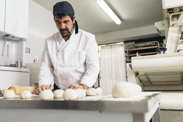 Panettiere impastare pasta in una panetteria. — Foto Stock