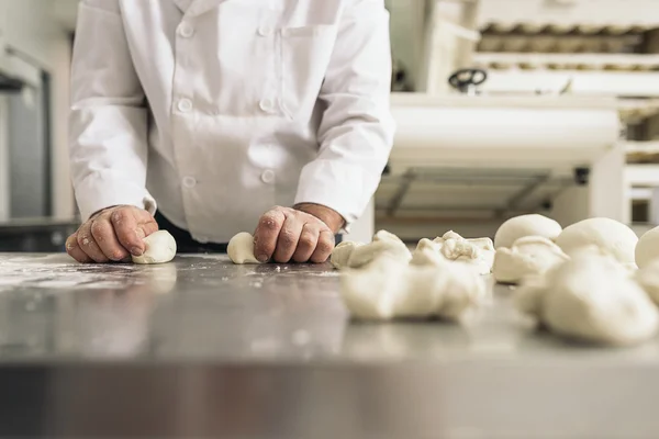 Baker pétrissant la pâte dans une boulangerie. — Photo