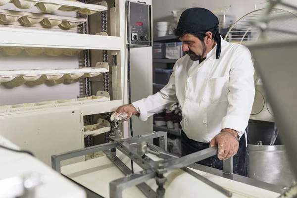 Panettiere impastare pasta in una panetteria. — Foto Stock