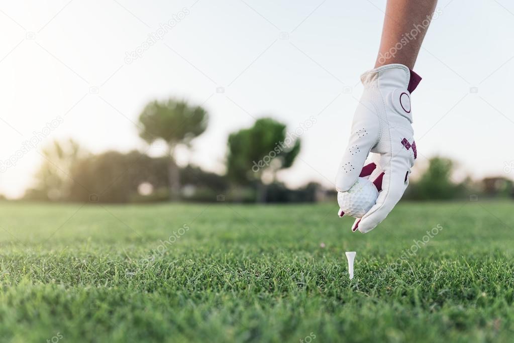 Hand woman putting a golf ball on the tee.