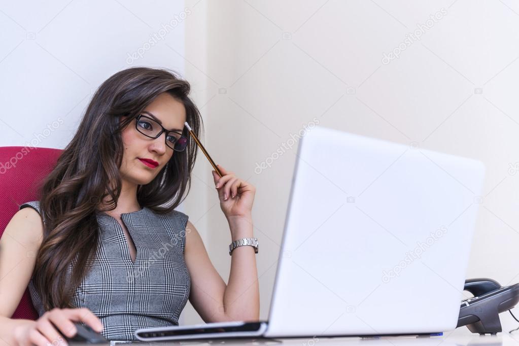 Beautiful business woman working on computer at her office