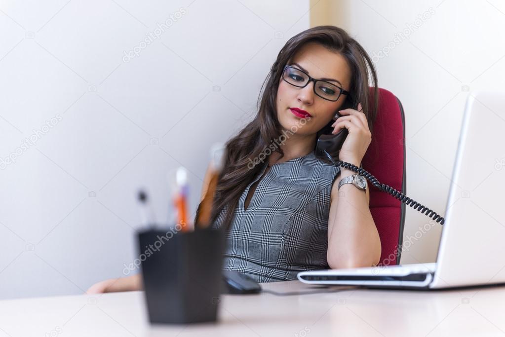 Business woman talking on phone and using her laptop