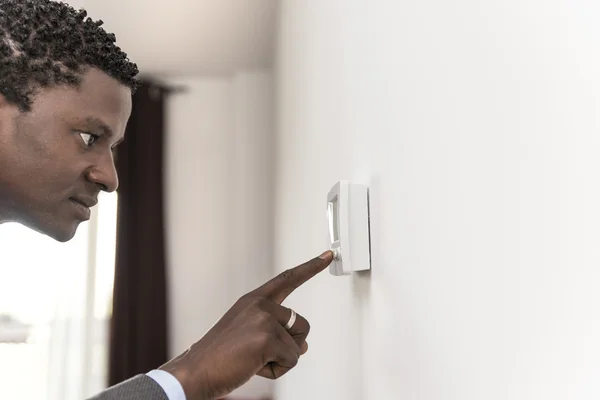 Afrikanisch-amerikanischer mann drücken knopf digitale klimaanlage — Stockfoto
