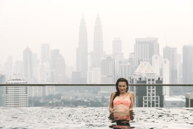 Şehir izlerken yüzme havuzunda güzel kadın