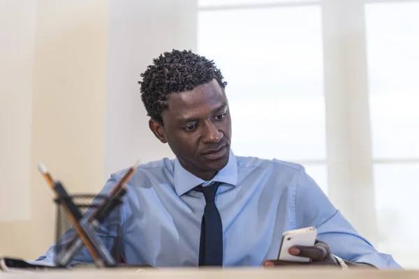 Empresário afro-americano na mesa usando smartphone — Fotografia de Stock