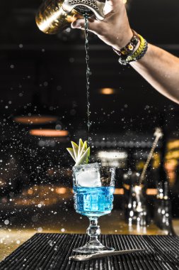 Barmen bardağa kokteyl dolduruyor.