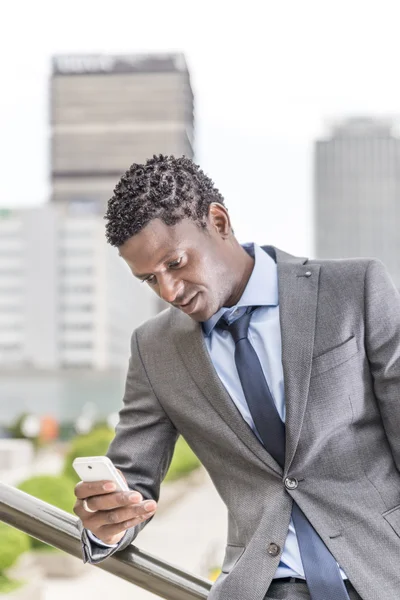 Homem de negócios Africano com smartphone sobre edifício de escritórios — Fotografia de Stock