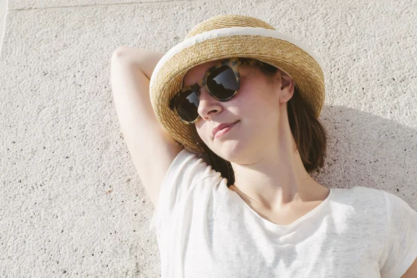 young casual girl wearing a hat and sunglasses relaxed