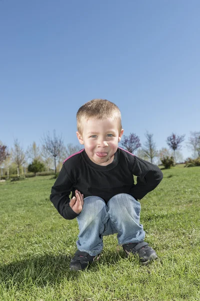Safado menino sticks fora língua ao ar livre — Fotografia de Stock