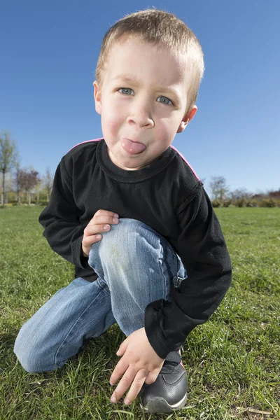 Travieso chico palos fuera lengua al aire libre — Foto de Stock