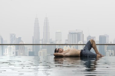 genç çekici adam gökdelen, çatıdaki yüzme havuzunda.