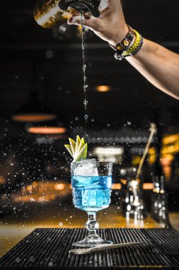 Barmen bardağa kokteyl dolduruyor.
