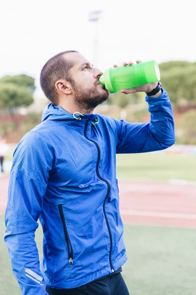 Corredor bonito após a corrida descansando e bebendo água — Fotografia de Stock