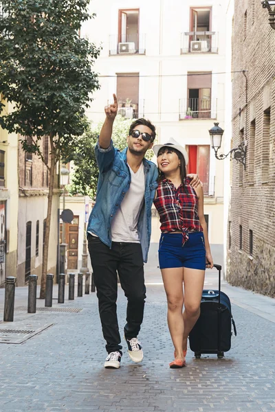 Tourist couple walking in city with suitcase