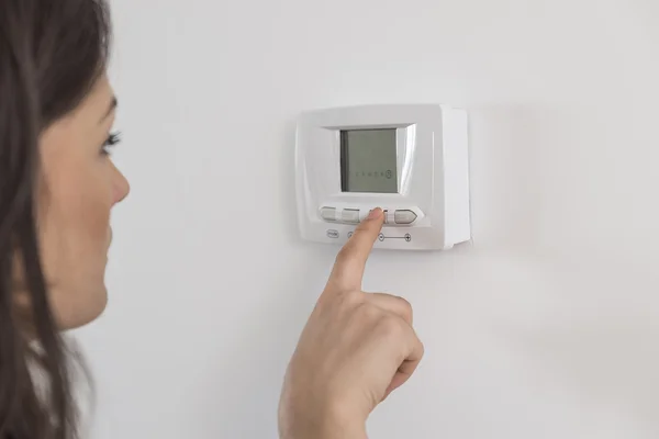 Beautiful happy woman push button digital thermostat at house — Stock Photo, Image