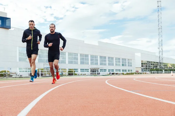 Grupo de jóvenes corriendo en el campo de atletismo —  Fotos de Stock