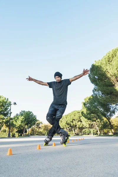 Urban young man on roller skates on the road at summer time