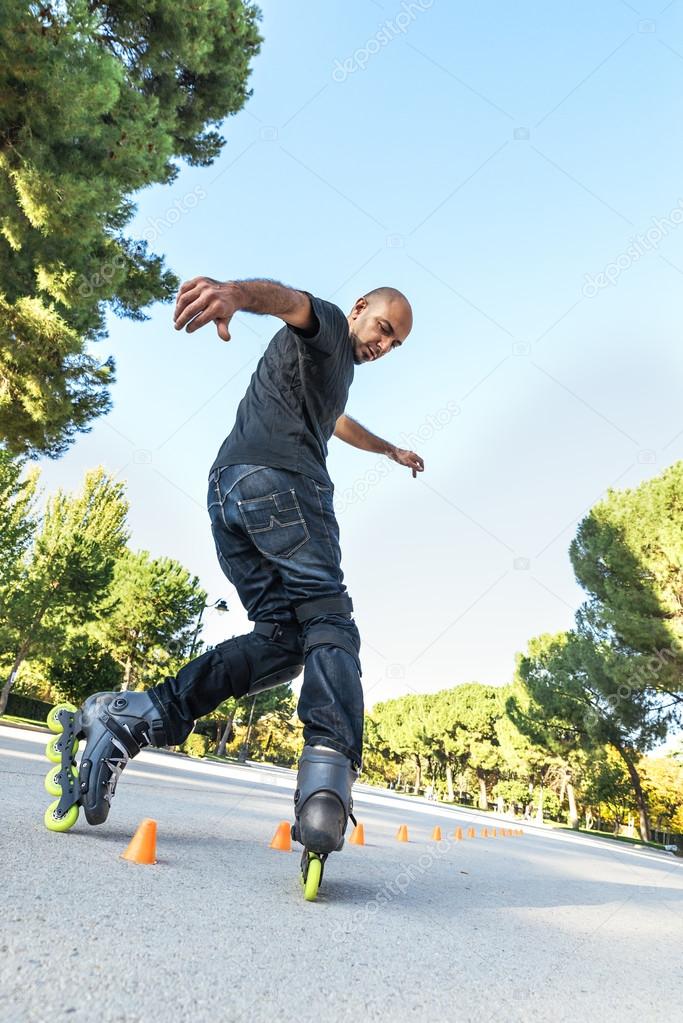 Urban young man on roller skates on the road at summer time