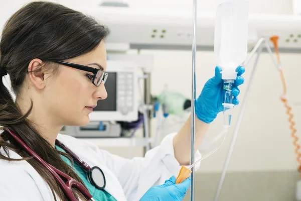 Young woman doctor anesthesiologist dressed in green gown, puts — Stock Photo, Image