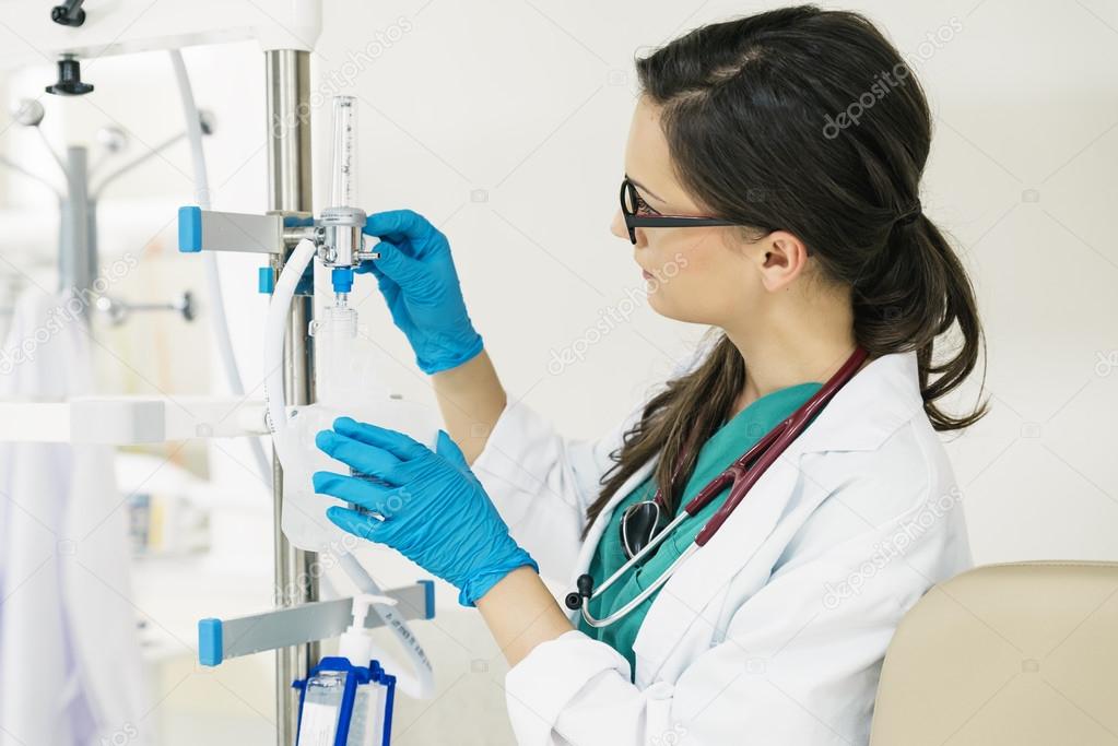 Young woman doctor anesthesiologist dressed in green gown, manip