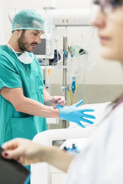 Male nurse putting on gloves in hospital — Stock Photo, Image