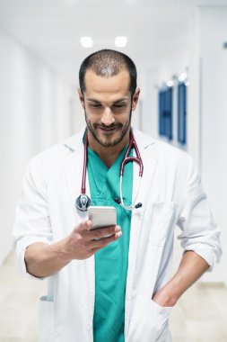 Güzel doktor hastanede cep telefonu üzerinde yazma