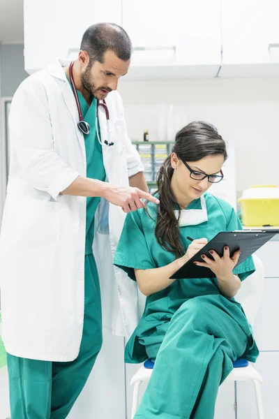 Médico y enfermero examinando informe del paciente — Foto de Stock