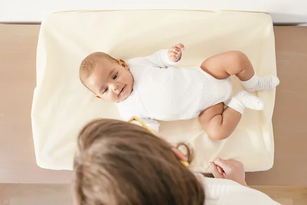 Madre cuidando a su bebé en el cambiador de bebés . — Foto de Stock