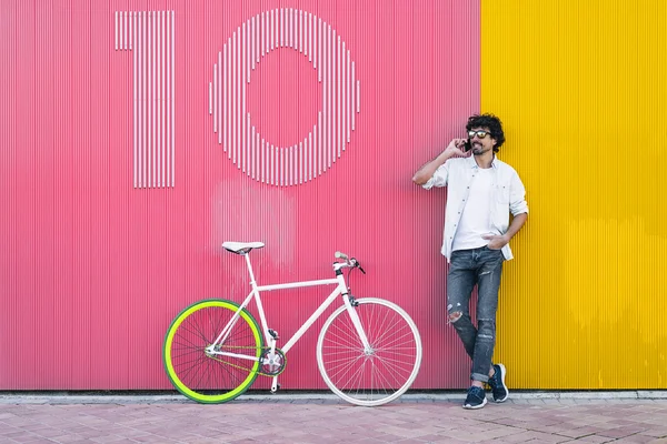 Schöner junger Mann mit Handy und Fahrrad mit festem Gang. — Stockfoto