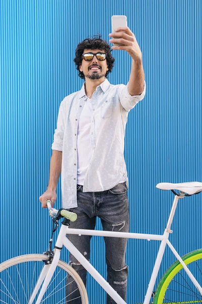 Schöner junger Mann mit Handy und Fahrrad mit festem Gang. — Stockfoto