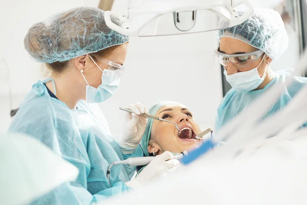 Dentistas con un paciente durante una intervención dental . — Foto de Stock