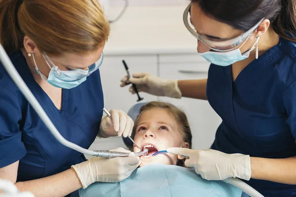 Дантисты с пациентом во время стоматологического вмешательства к девушке . — стоковое фото