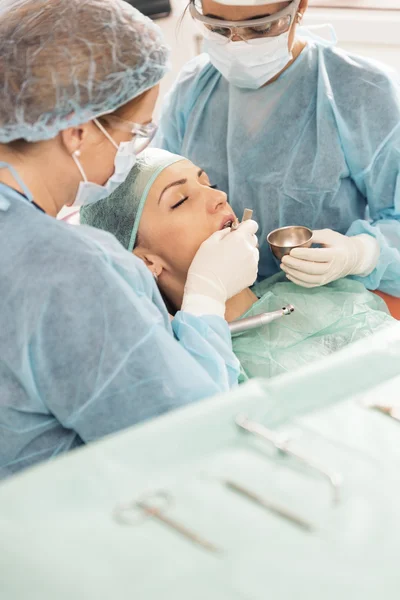 Οδοντίατροι με έναν ασθενή κατά τη διάρκεια μια οδοντιατρική παρέμβαση. — Φωτογραφία Αρχείου