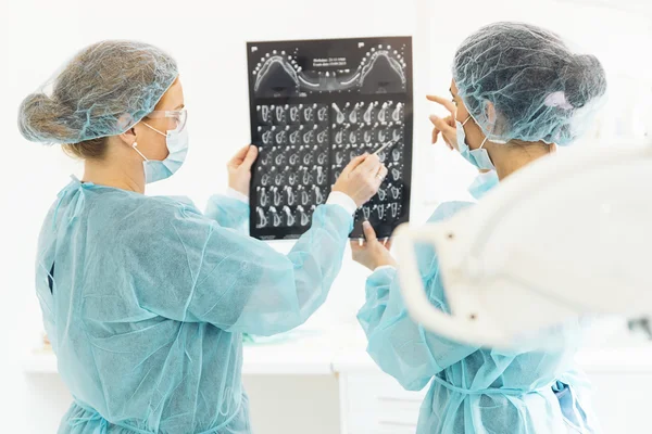 Dentist showing something to her colleague on x-ray image. — Stock Photo, Image